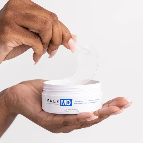 Hands using tweezers to take an eye mask out of the jar Hands using tweezers to take an eye mask out of the jar